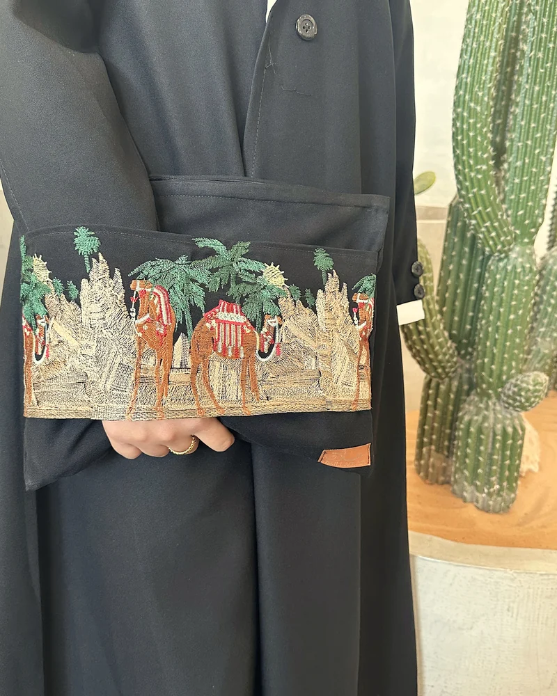 حقيبة يد مطرّزة برسم قافلة جمال ونخيل بخيوط ذهبية