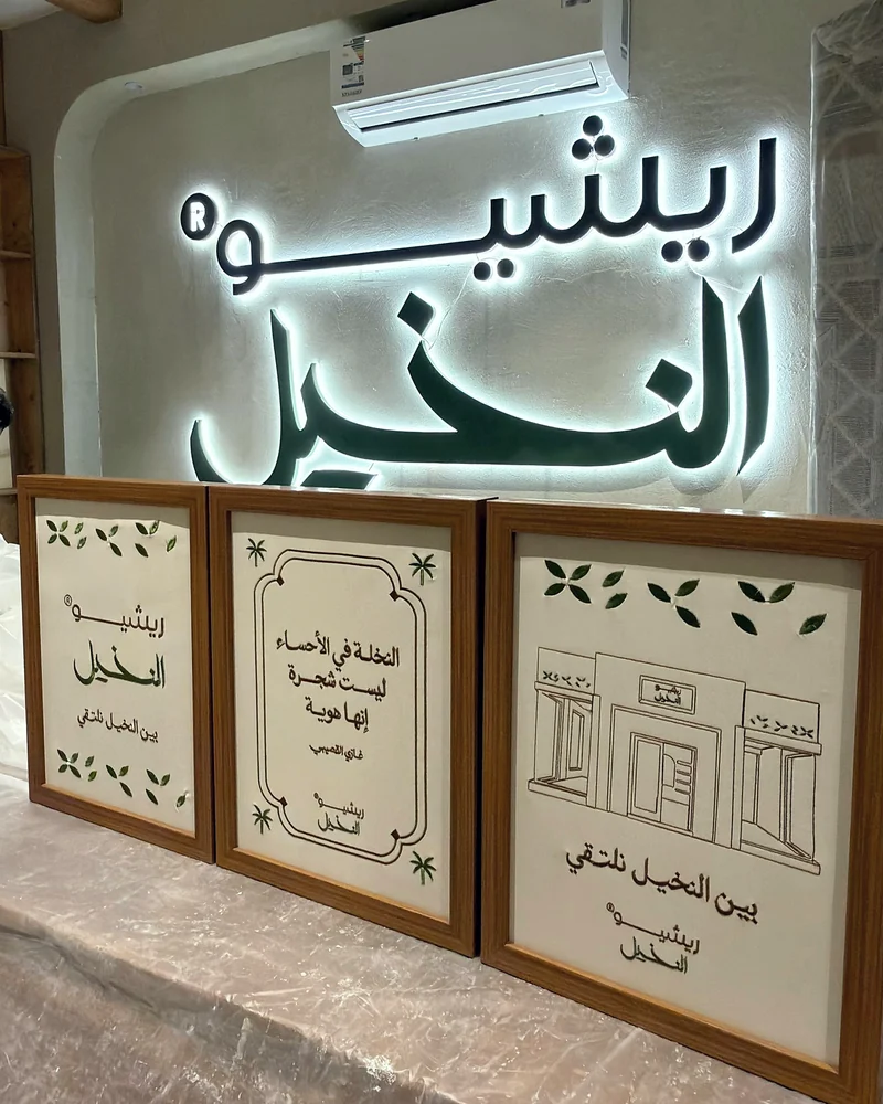 سلسلة لوحات مؤطّرة من رسومات خلّاق معروضة داخل ريشو النخيل